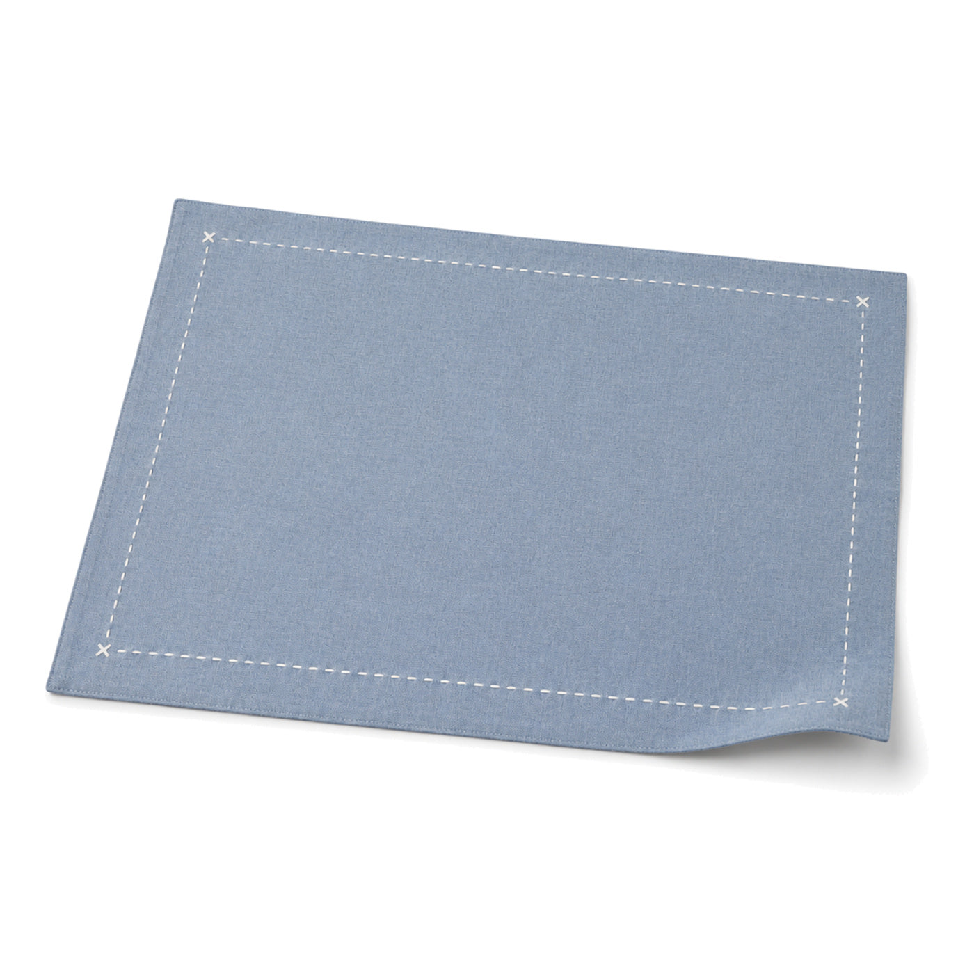 Dusty blue contrast-stitch placemat shown in a premium angled presentation, lightweight table linen by Primeval
