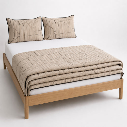 Beige and black minimalist line art cotton quilt, folded with matching pillows for wholesale bedding sourcing