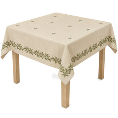 Primeval beige olive botanical embroidered border tablecloth displayed on a square dining table
