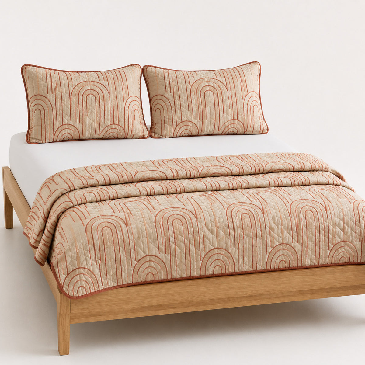 Beige and terracotta modern arch cotton quilt, folded with matching pillows for wholesale bedding sourcing