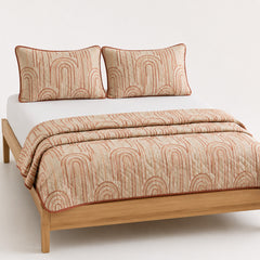 Beige and terracotta modern arch cotton quilt, folded with matching pillows for wholesale bedding sourcing