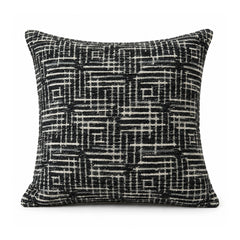 Primeval black and ivory cushion with an intricate interlocking linear maze and broken grid pattern