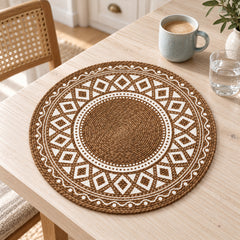 Mocha brown round placemat with an ivory diamond lattice border, small dotted rings and a textured circular centre on a light wooden dining table