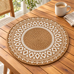 Round caramel-brown and ivory placemat with a central concentric spiral and geometric diamond border on an oak dining table
