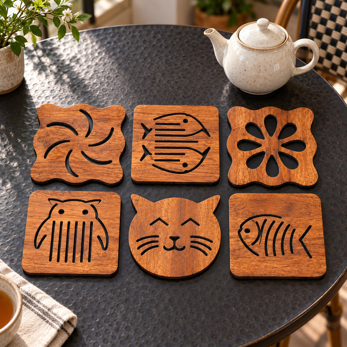 Set of six warm brown wood-look coasters with varied decorative cutout motifs including a cat face, fish, owl and flower on a black stone table