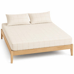 Cream and beige windowpane bed sheet set with matching pillowcases on a wooden bed