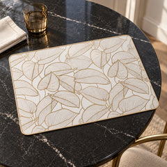 Ivory rectangular dining placemat with delicate golden botanical leaf outlines on a dark marble table