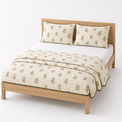 Cream and olive leaf print cotton quilt, folded with matching pillows for wholesale bedding sourcing