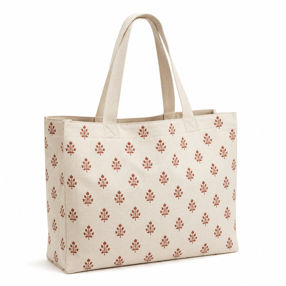 Cream tote bag with small rust artisan-style printed motifs and natural handles on a white background.