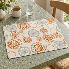 Ivory rectangular placemat with repeating circular botanical medallions in rust orange and slate grey on a speckled dining table
