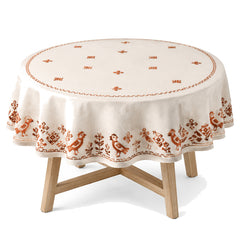 Primeval cream rust folk embroidery tablecloth displayed on a round dining table
