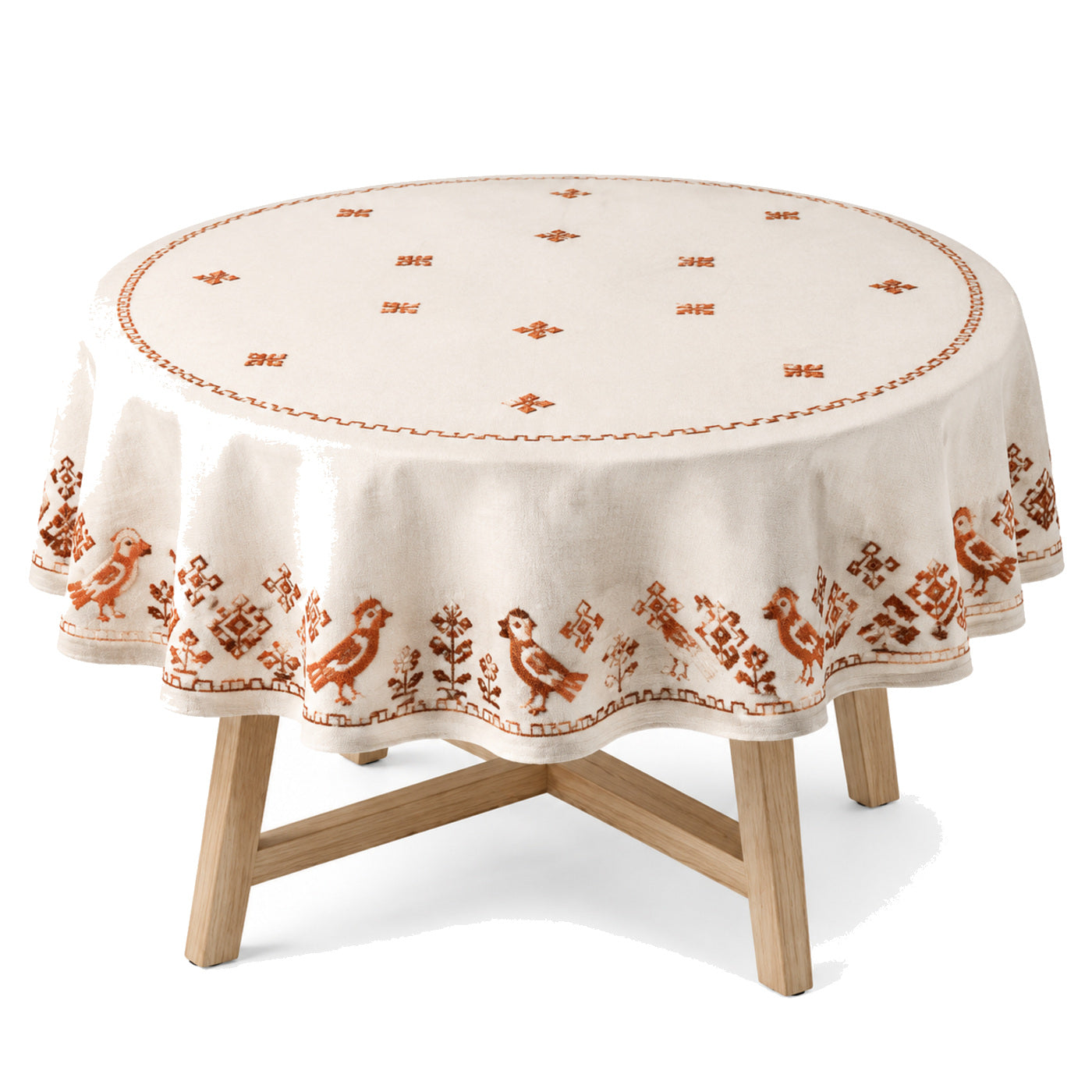 Primeval cream rust folk embroidery tablecloth displayed on a round dining table
