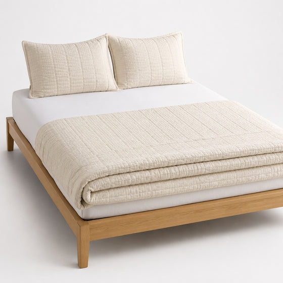 Cream waffle-texture cotton quilt, folded with matching pillows for wholesale bedding sourcing