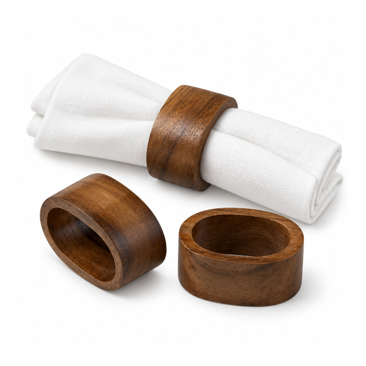 Three chunky dark walnut-tone wooden napkin rings with smooth rounded edges, including one ring around a folded white cloth napkin