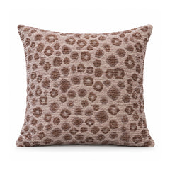 Primeval dusty rose and mocha brown cushion with scattered leopard-inspired animal spots on a muted pink ground