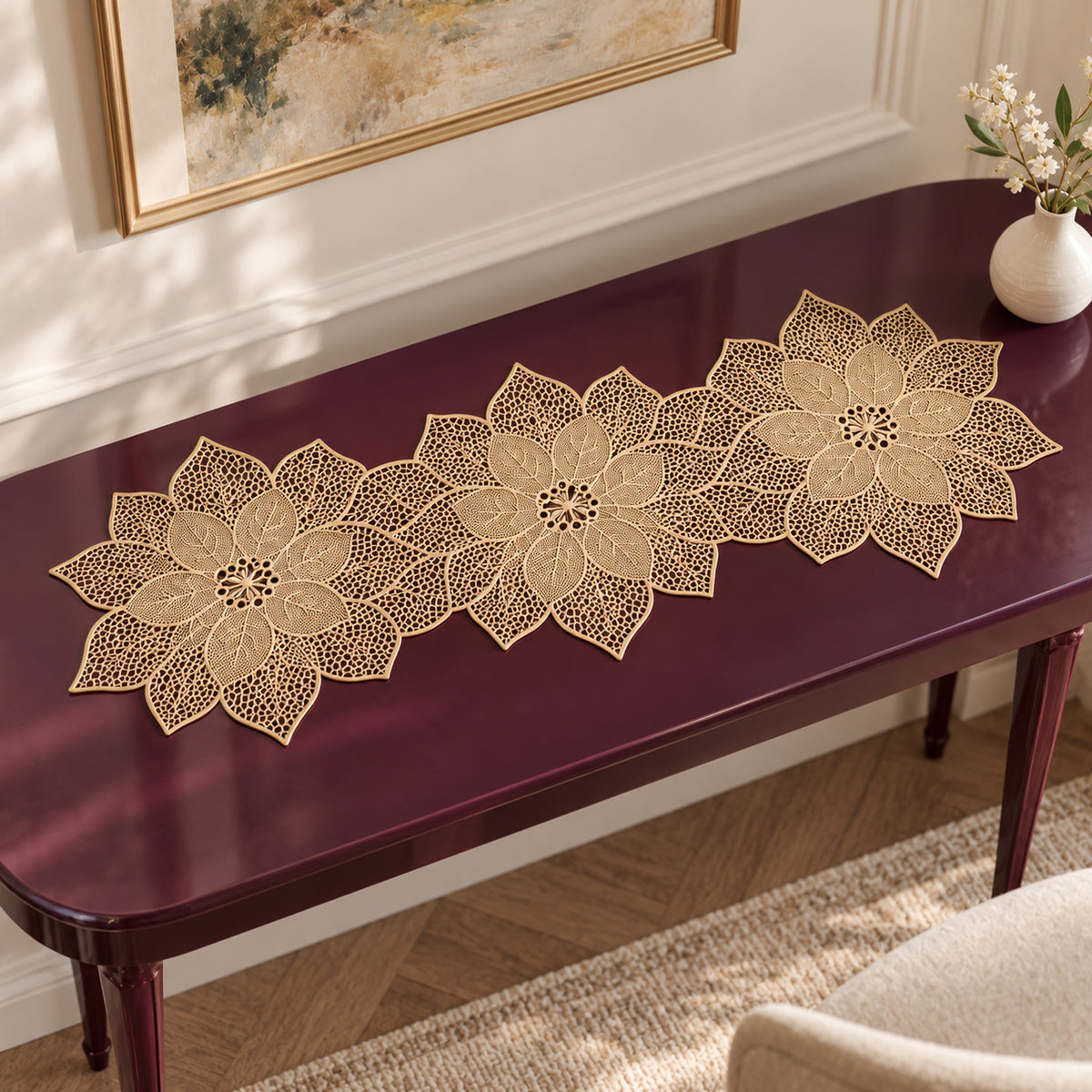 Elongated gold lace-look decorative table runner formed from linked openwork flower motifs arranged across a burgundy console table