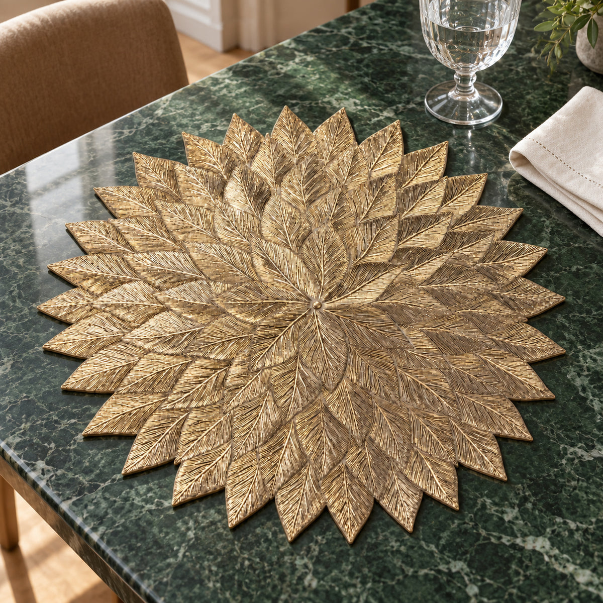 Metallic gold leaf cutwork placemat in a round floral shape on a dark tabletop