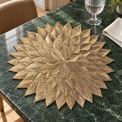 Metallic gold leaf cutwork placemat in a round floral shape on a dark tabletop