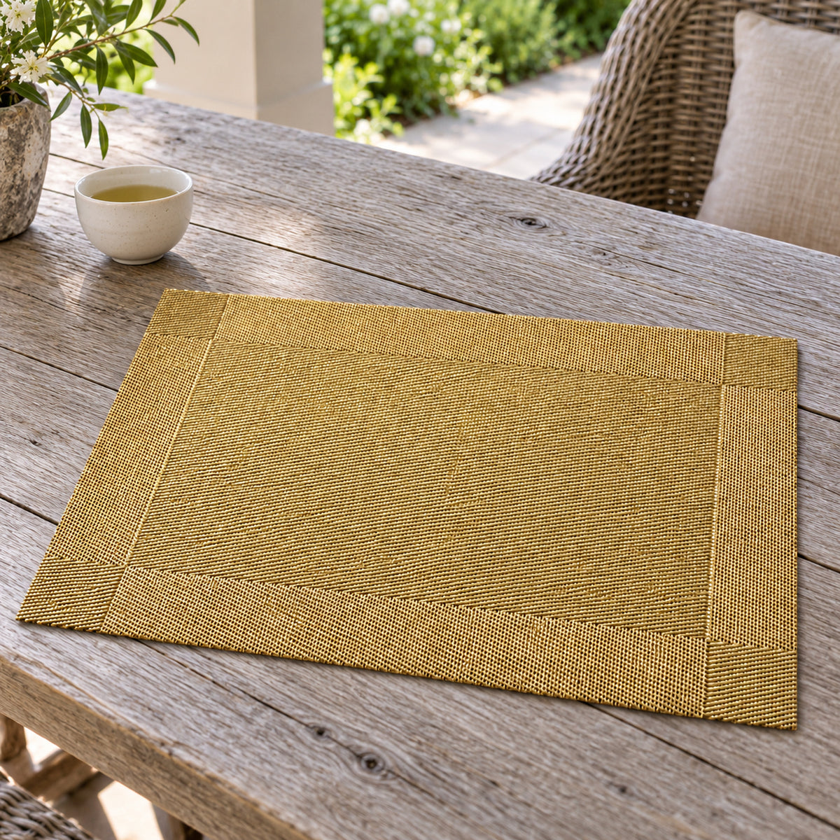 Champagne gold rectangular placemat with fine woven-look texture and defined border on a weathered wood table