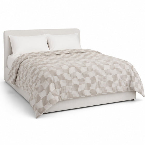 Primeval greige and ivory wavy checkerboard duvet cover displayed on a styled bed against a clean white studio background