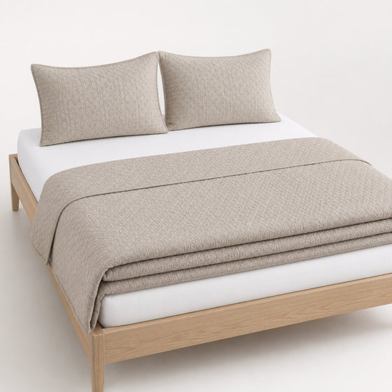Greige jacquard micro-geometric cotton quilt, folded with matching pillows for wholesale bedding sourcing