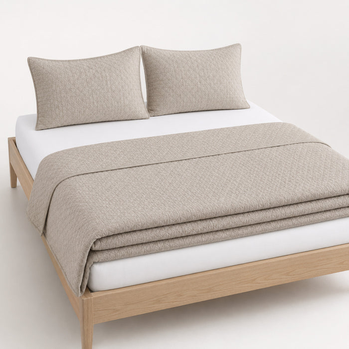 Greige jacquard micro-geometric cotton quilt, folded with matching pillows for wholesale bedding sourcing