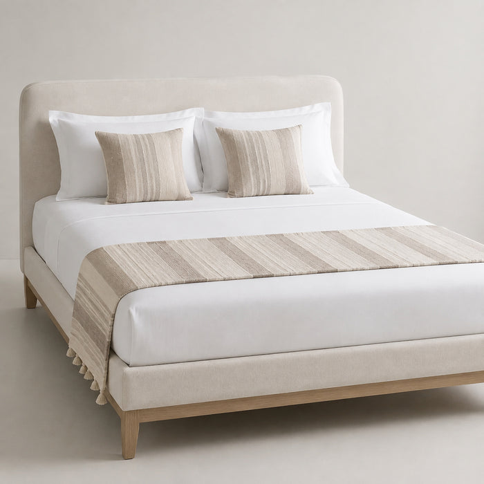 Greige wide-stripe bed runner with subtle fringe, styled on white bedding for wholesale hospitality and private-label sourcing