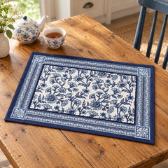 Indigo and white rectangular placemat with a detailed floral block-print-style centre and decorative blue border on a wooden table