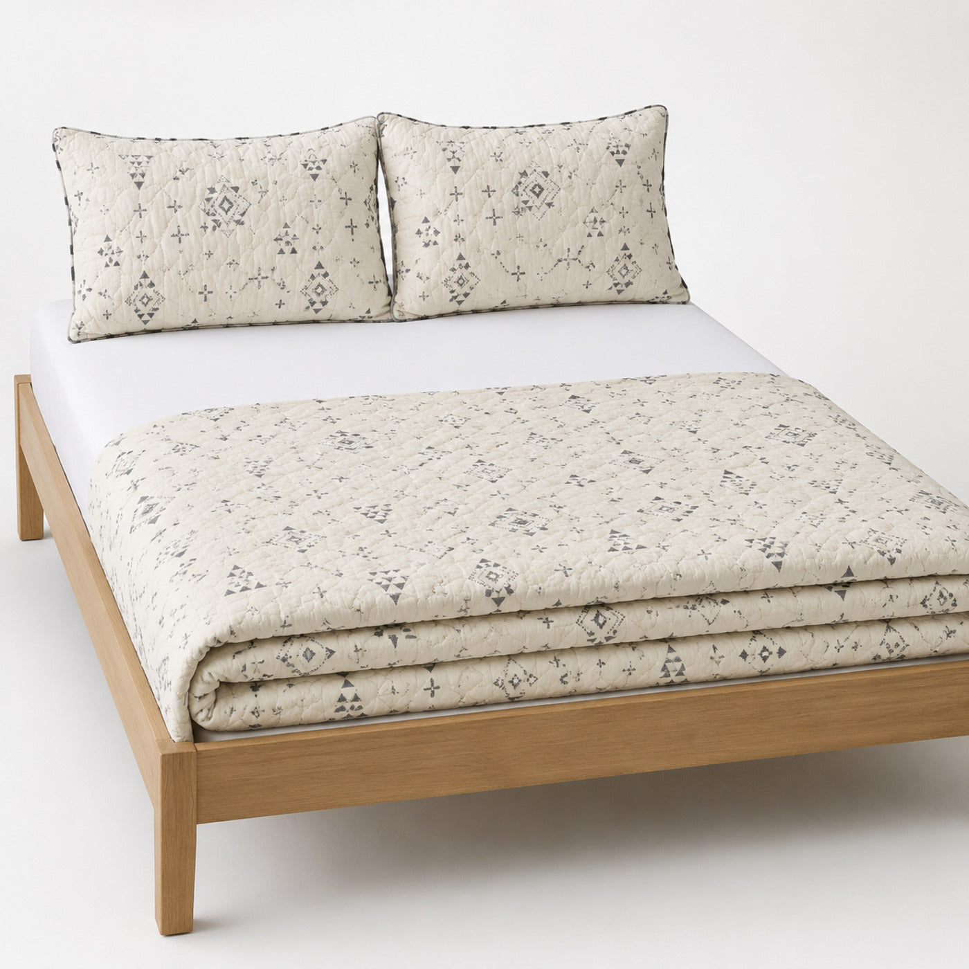 Ivory and charcoal Scandinavian geometric cotton quilt, folded with matching pillows for wholesale bedding sourcing