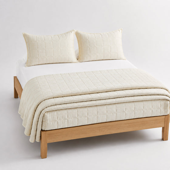 Ivory dobby micro-texture cotton quilt, folded with matching pillows for wholesale bedding sourcing