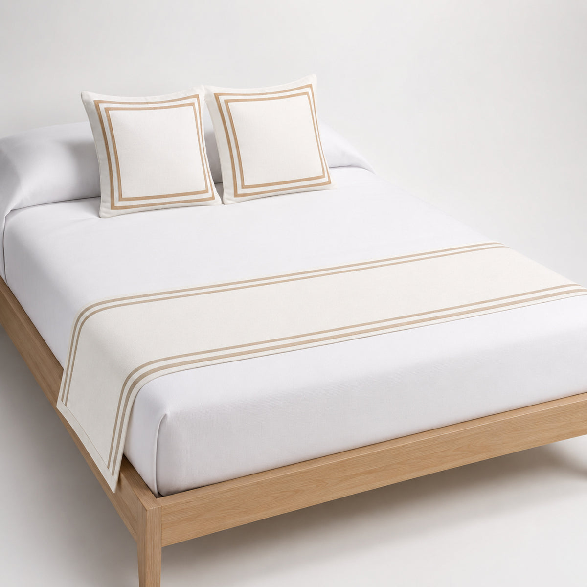 Ivory bed runner with refined double stripe border, styled on white bedding for wholesale hotel and home textile sourcing