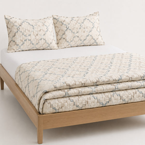 Ivory dusty blue and taupe abstract lattice cotton quilt, folded with matching pillows for wholesale bedding sourcing