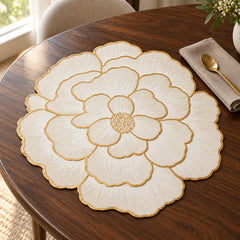 Scalloped ivory floral placemat with gold outlines on a dark wooden dining table
