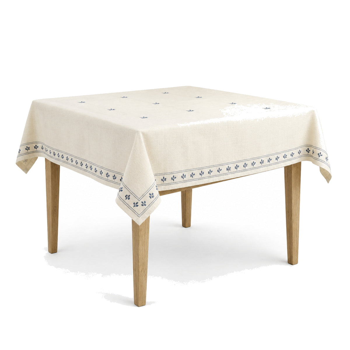 Primeval ivory muted blue embroidered border tablecloth displayed on a square dining table