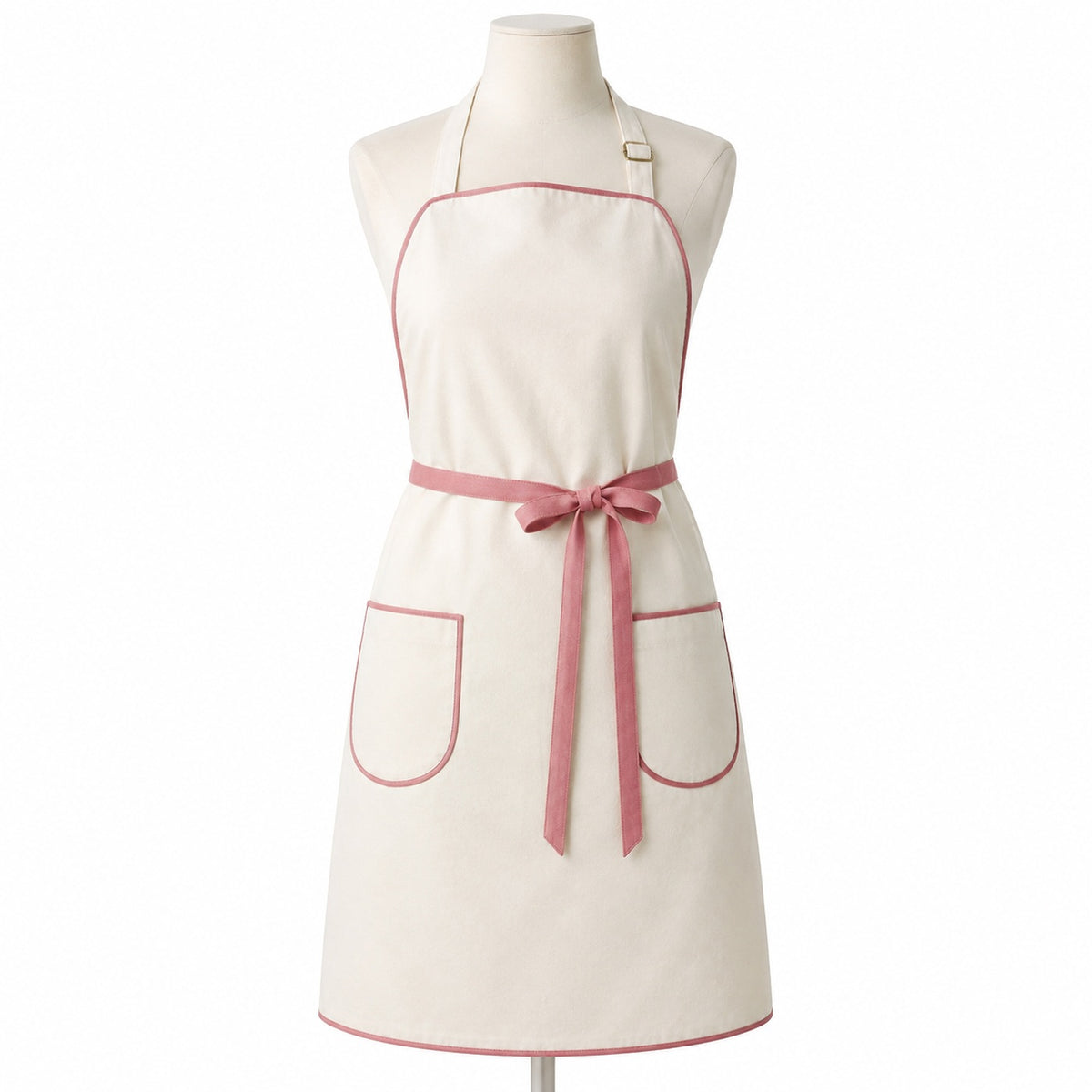 Primeval ivory chef apron with muted rose piping and pockets displayed on a dress form