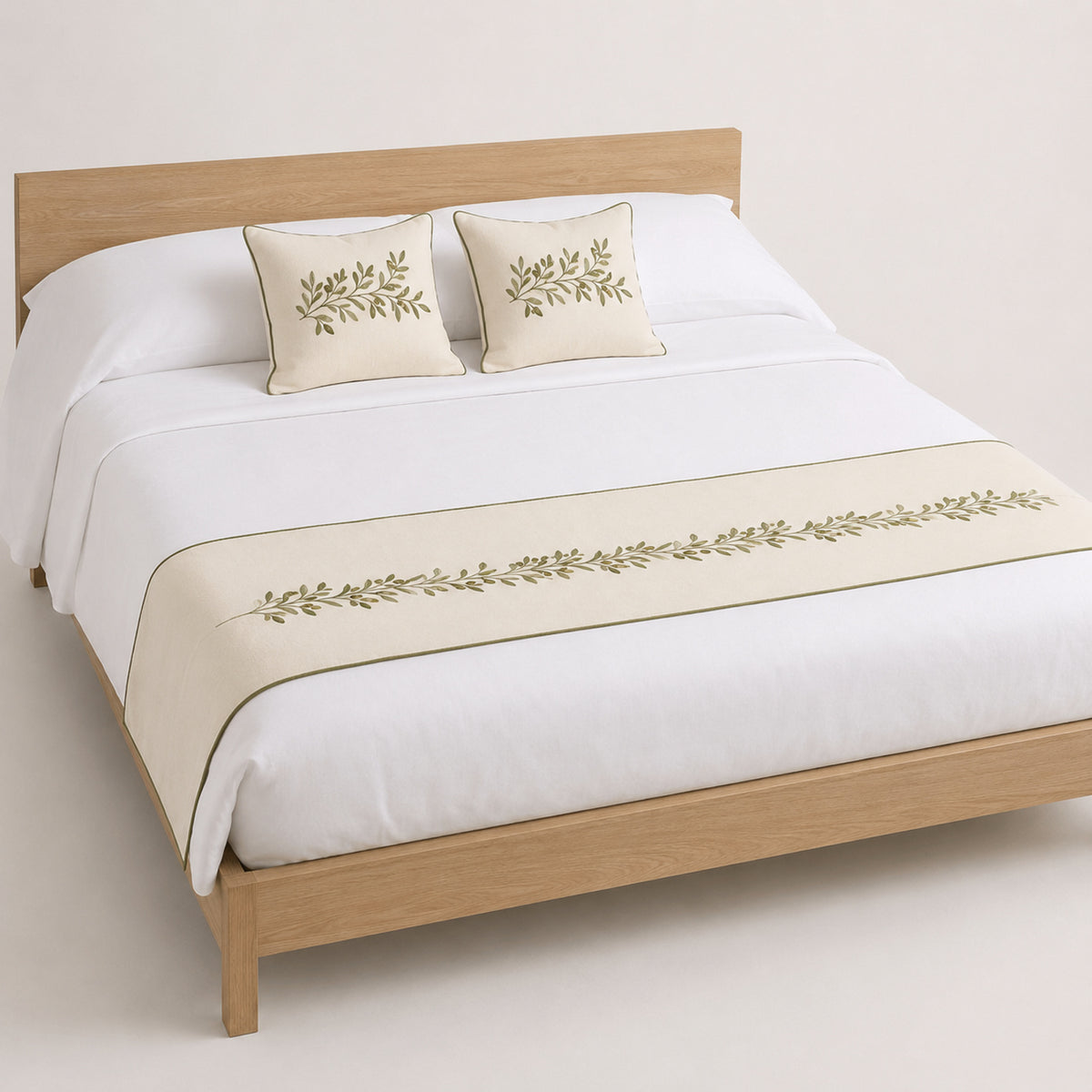 Ivory and olive botanical border bed runner styled on white bedding for wholesale resort, boutique hotel and private-label sourcing