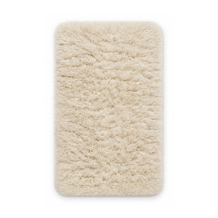 Ivory plush shag bath mat on white background