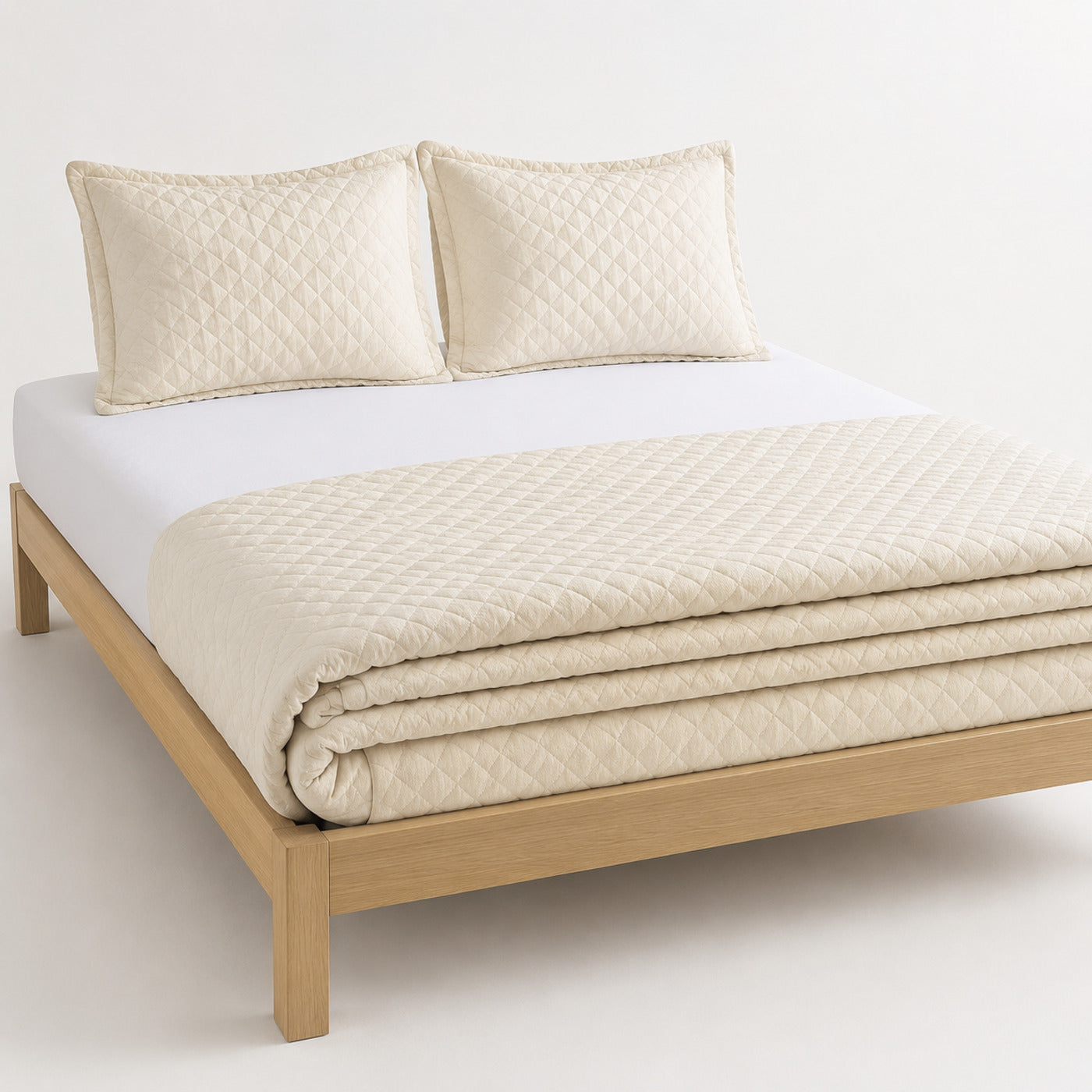 Ivory tonal diamond boutique-style cotton quilt, folded with matching pillows for wholesale bedding sourcing