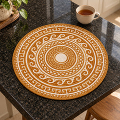 Round mustard and white ornamental mandala placemat on a dark stone tabletop