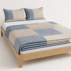 Natural dusty blue and beige abstract stripe block cotton quilt, folded with matching pillows for wholesale bedding sourcing