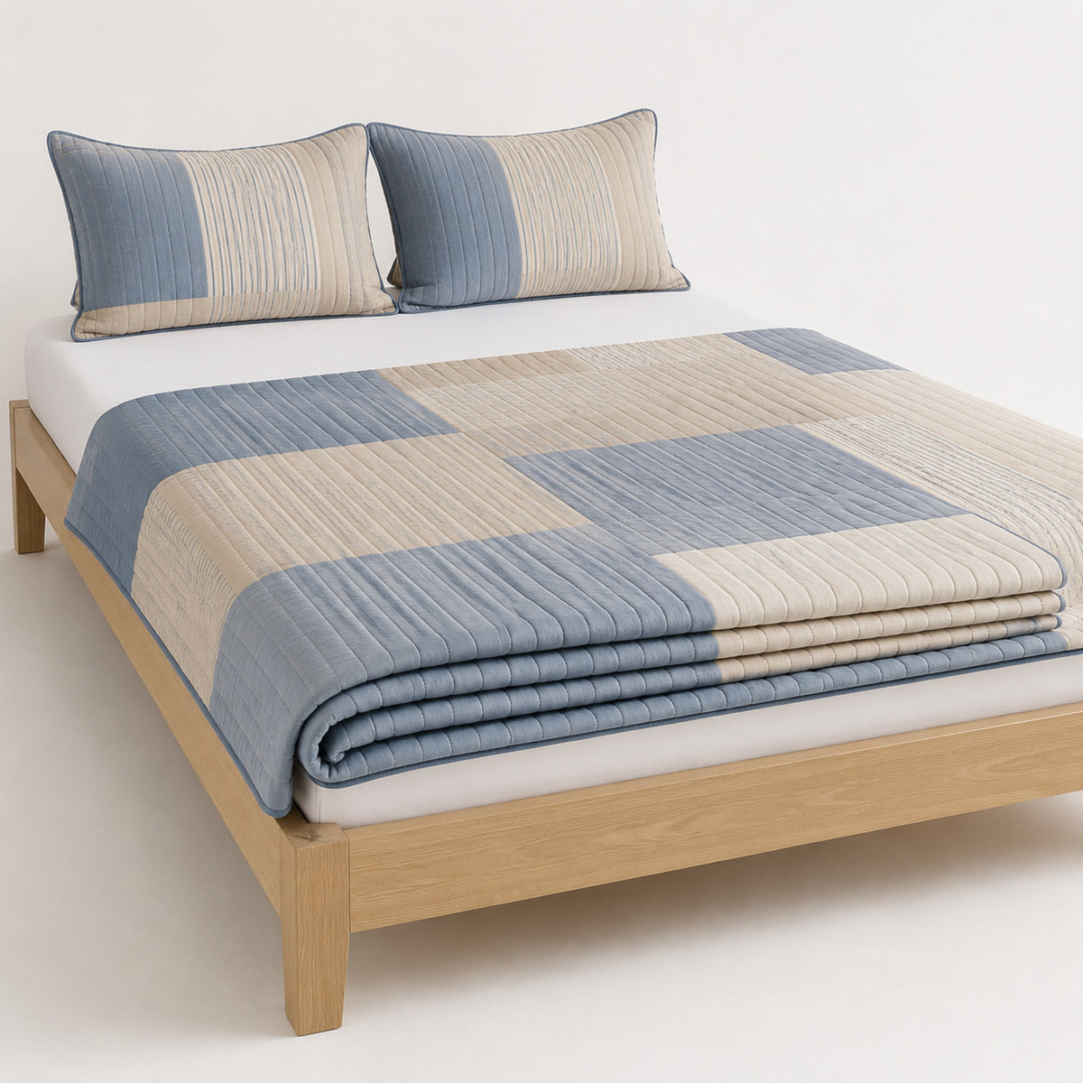 Natural dusty blue and beige abstract stripe block cotton quilt, folded with matching pillows for wholesale bedding sourcing