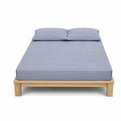 Navy and white fine-stripe bed sheet set with matching pillowcases on a wooden bed