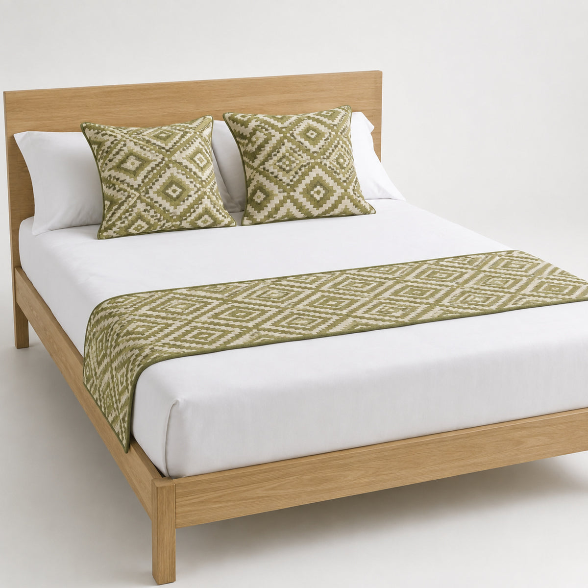 Olive diamond geometric bed runner styled on white bedding for wholesale resort, boutique hotel and private-label sourcing