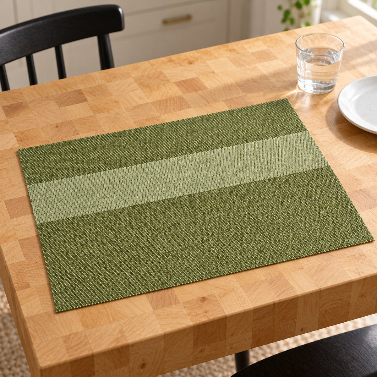 Rectangular olive green placemat with light sage broad horizontal centre stripe and darker moss green bands on a pale wood dining table