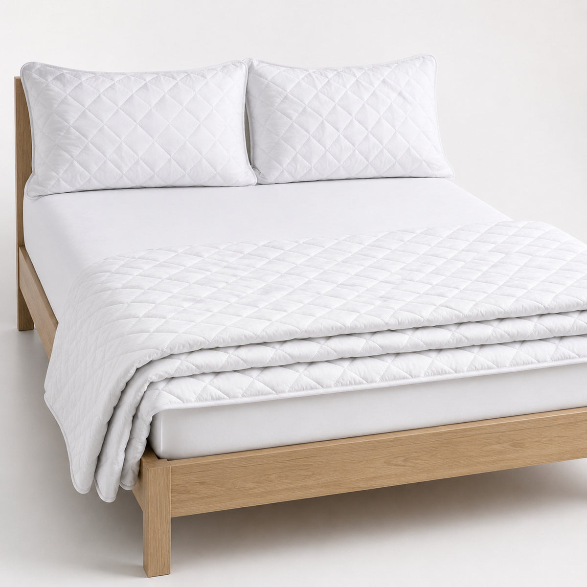 Pure white hotel-style diamond quilted cotton quilt, folded with matching pillows for wholesale bedding sourcing