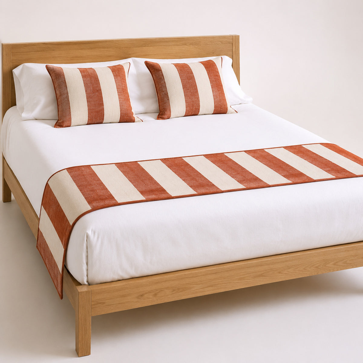 Rust and ivory bold-stripe bed runner styled on white bedding for wholesale hospitality, resort and private-label sourcing