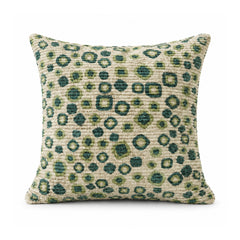 Primeval sage green and olive cushion with teal outlined leopard-inspired spots scattered across a light ground