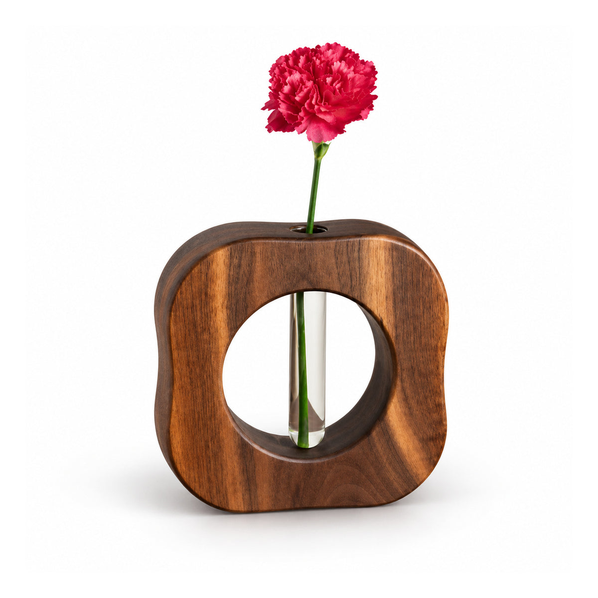 Small sculptural square wood bud vase with a large circular cutout, narrow glass stem tube and single pink flower