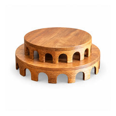 Two stacked low round wooden risers with honey-brown tops and repeated scalloped arch-shaped cutouts around their sides