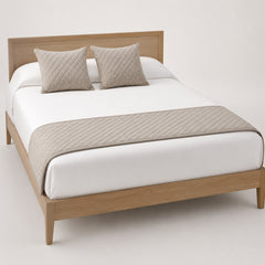 Taupe diamond-quilted bed runner styled across white bedding for wholesale hotel, resort and private-label sourcing